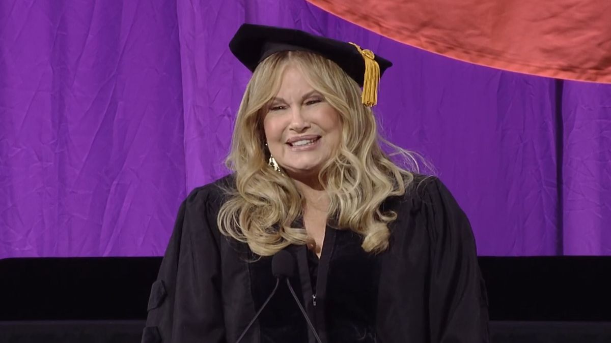 Jennifer Coolidge speaking at Emerson College commencement 2025, smiling in front of graduating students